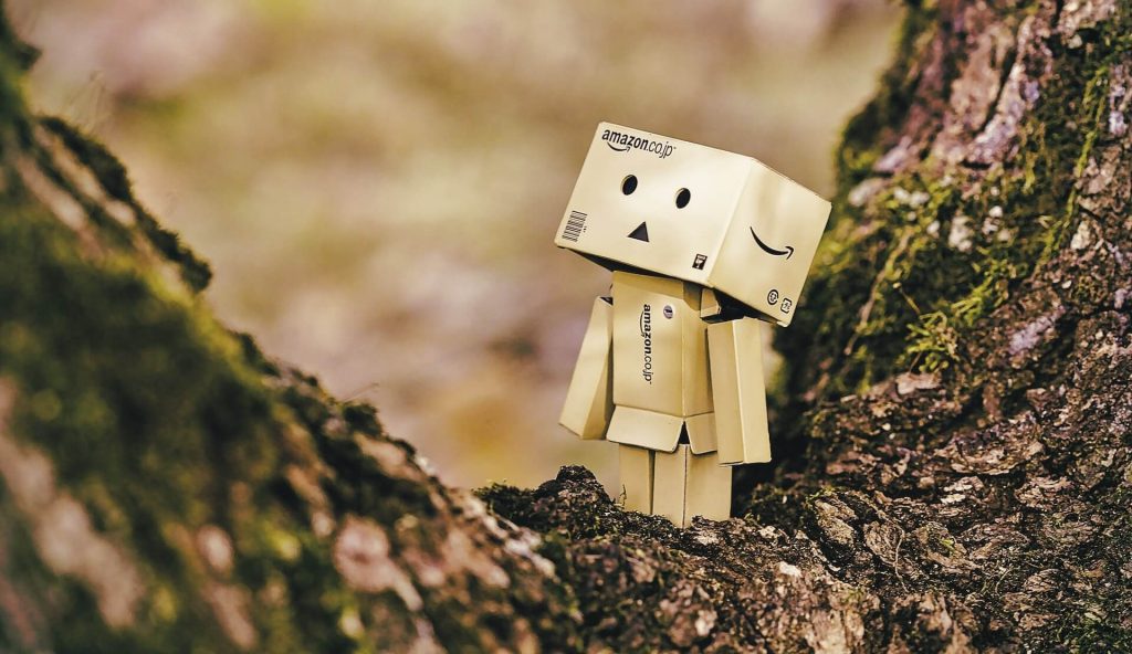 Pequeño muñeco elaborado con cajas de Amazon colgado de un árbol