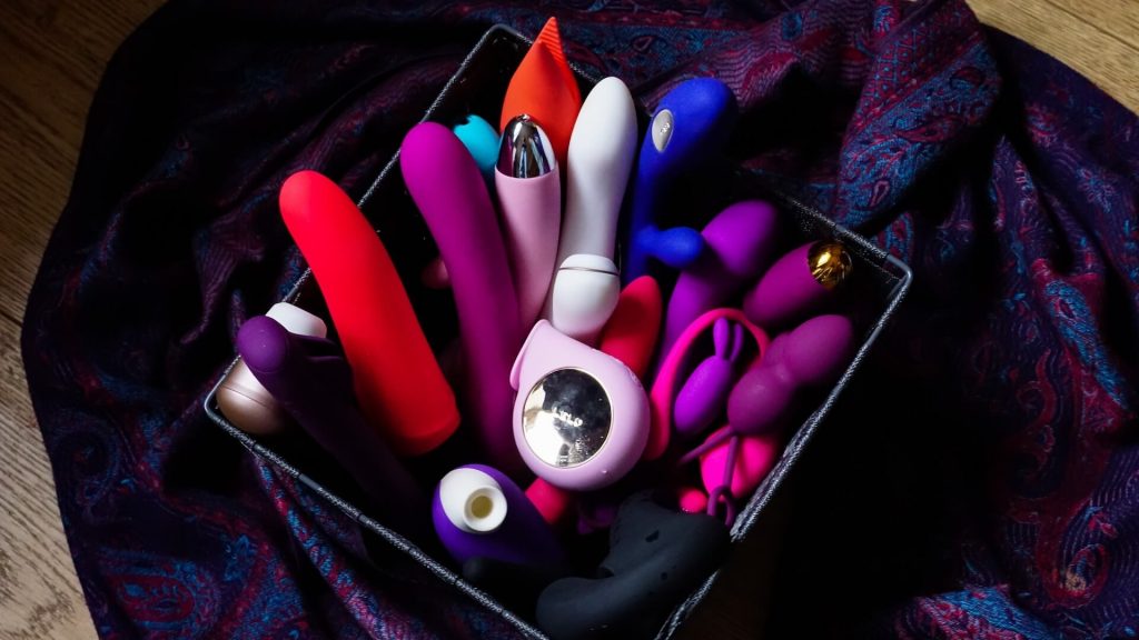 Una cesta llena de diferentes tipos de consoladores y juguetes sexuales